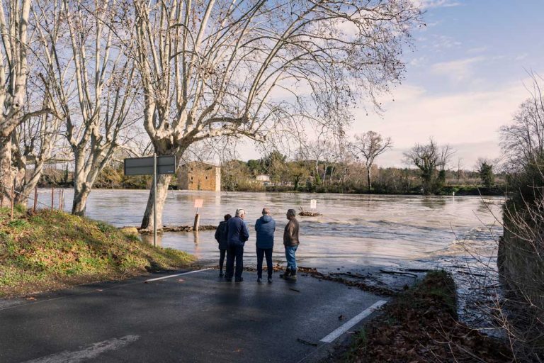 Residents look on as rising floodwaters cut off a local road, underscoring the need for stronger community preparedness.