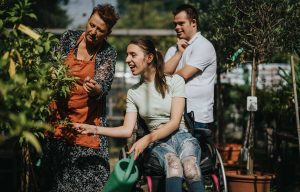 Three people attend to a garden. One is in a wheelchair